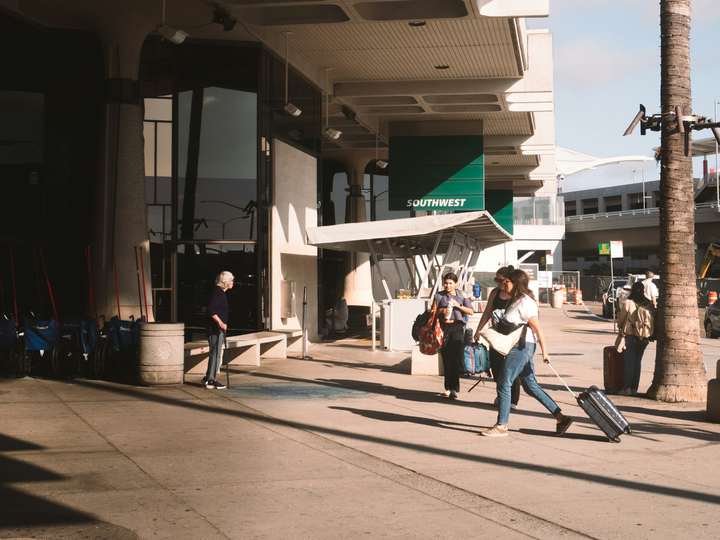 A traveler with a rolling suitcase outside an airport terminal